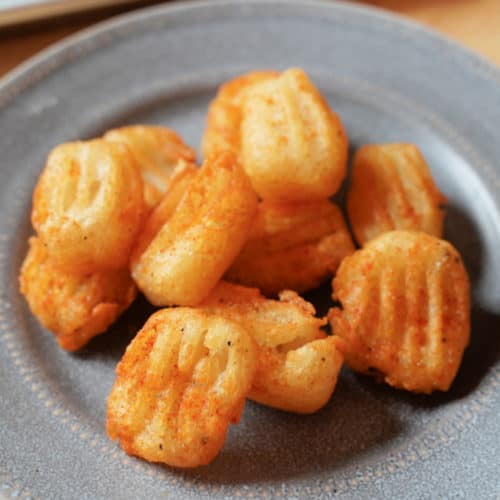 A grey plate with golden brown potato pillows.