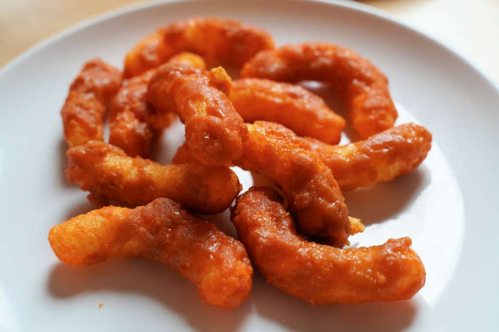 A plate of toffee coated cheese puffs on a white plate