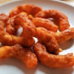 A plate of toffee coated cheese puffs on a white plate