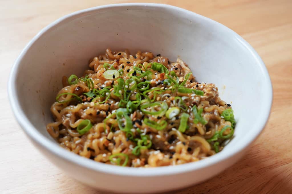 A bowl of everything bagel seasoning ramen with green onions in a white bowl.