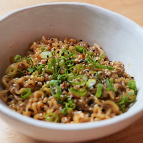 A bowl of everything bagel seasoning ramen with green onions in a white bowl.