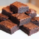 Squares of brownies stacked on white plate.