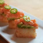 Four crispy salmon sushi on lined up on a plate.