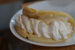 Folded waffle "taco" with cream cheese/whipped cream filling swirling out.