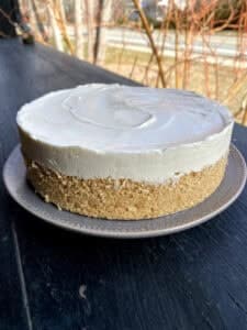 Two layer tart resting on white plate. Top layer of icing, bottom layer of Teniis brand biscuits.