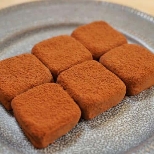 eight squares of choocolate truffles on a round dinner plate.