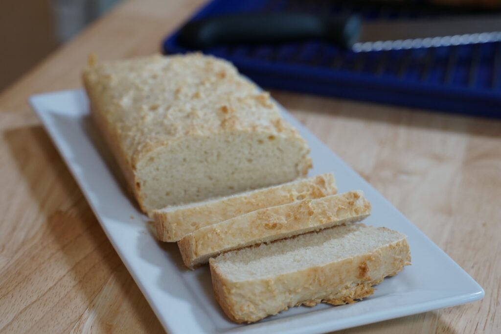 Dense, sliceable loaf of rice flour bread on a rectangular, white serving dish.
