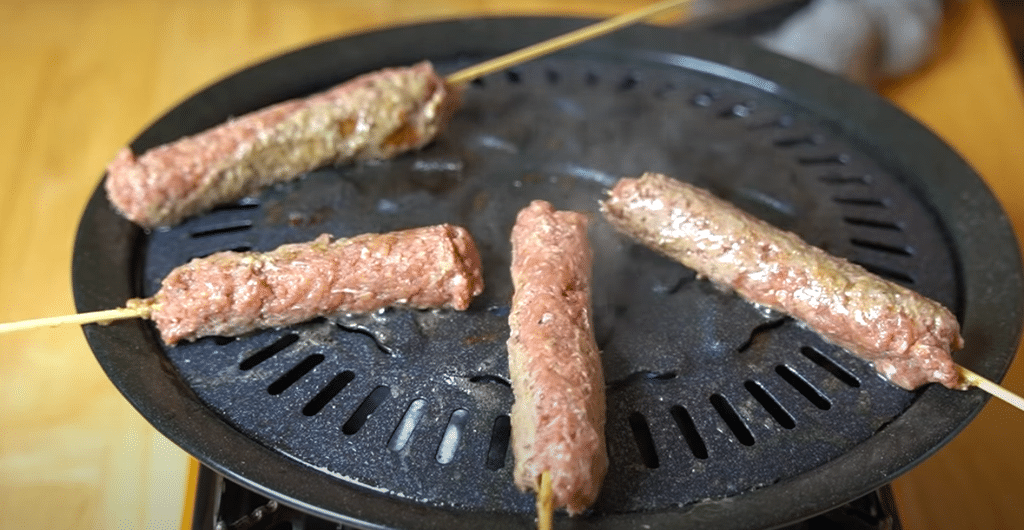 Four kabobs skewered and cooking away on a single burner grill top.